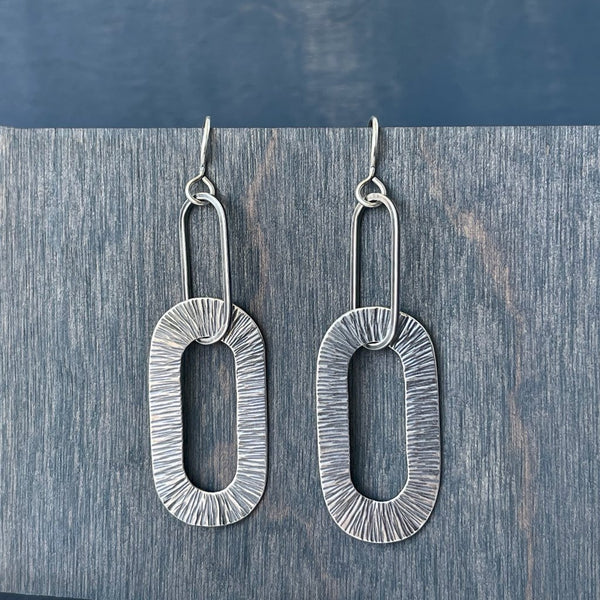 Handmade Earrings using oxidized sterling silver. Hammered to create a subtle yet graphic texture. Oval shape, dangle earrings